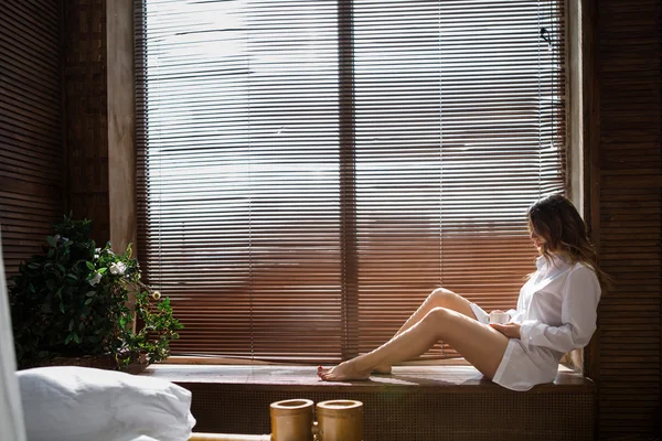 Chica sentada junto a la ventana — Foto de Stock