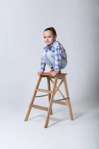 Preschooler in regular clothes sits on a chair squatting — Stock Photo, Image