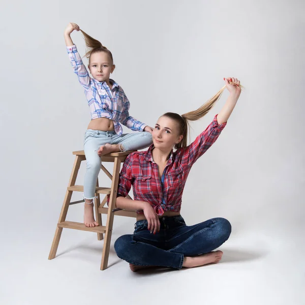 Atletische moeder en dochter show haar terwijl zitten op stoel en vloer — Stockfoto
