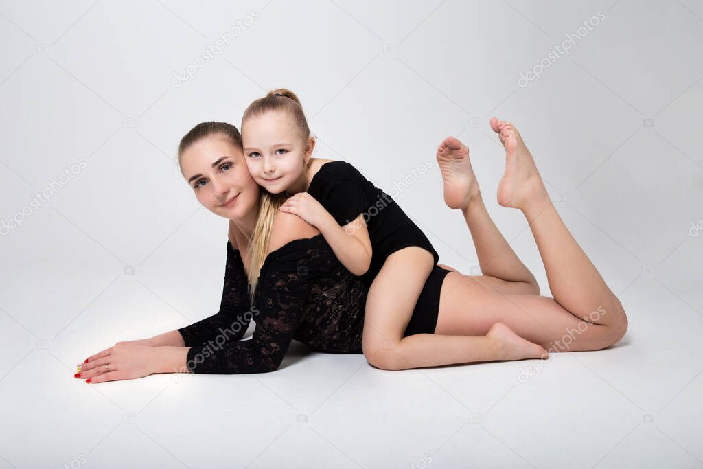 mom flexes in gymnastic position daughter hugs mom
