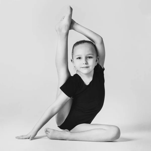 Weinig turner toont flexibiliteit en evenwicht in een gymnastiek pose — Stockfoto