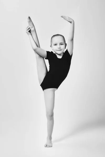 Weinig turner toont flexibiliteit en evenwicht in een gymnastische houding door het optillen van haar been — Stockfoto