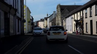 LLANDOVERY, WALES, UNITED KINGDOM - CIRCA EPTEMBER, 2020: High Street 'teki renkli Galler şehir merkezinde beyaz Mini arabayı takip eden açık hava kafede oturan insanlar.