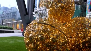 Londra şehrinin gökdelenleri, camları ve metal yapım tasarımları arasındaki yerde Noel süslemeleri için büyük altın renkli topları yukarı kaldırın..