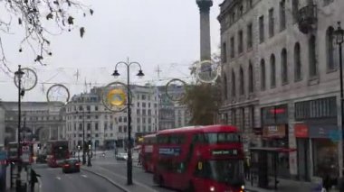 Londra, İngiltere, UNITED KINGDOM - CIRCA NOVEMBER, 2020: Trafalgar Meydanı 'ndaki sokak Noel süsleri, insanlar ve kırmızı çift katlı otobüsler.