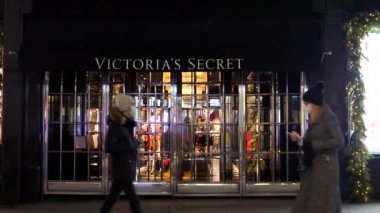 LONDON, ENGLAND, UNITED KINGDOM - 28, Kasım 2020: Çocuklu aileler Victoria 's Secret American iç çamaşırı, kıyafet ve güzellik zinciri perakende mağazası girişinin önünden gece geçtiler