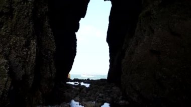 Parlak denizden geçen turist teknesi karanlık uçurumdaki yüksek dikey boşluktan görülüyor..