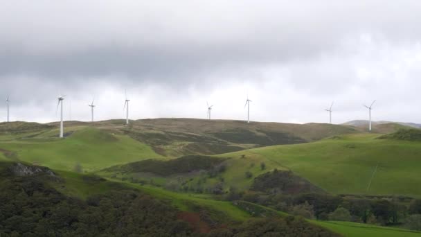 アベリストウィス近くのウェールズの丘の上の風力タービン 代替エネルギー源のハンドヘルドカメラショット — ストック動画