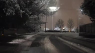 Gece karda araba ön cam manzaralı. Manchester 'daki Trafford Merkezi' nin yakınındaki yol kenarında devriye arabasının yanından geçiyoruz. İngiltere 'nin kuzeybatısında kışın nadiren kar yağar..