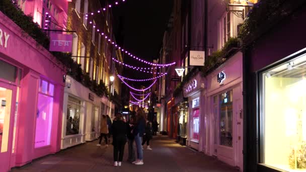 ロンドン イングランド イギリス Circa 2020年11月 夜のソーホーのカラビーストリートで有名なピンク色の照明で疑問に思っている観光客 — ストック動画