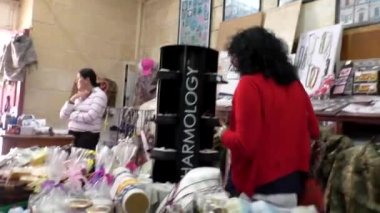 MDINA, MALTA - CIRCA MAYIS 2015: Malta hediyelik eşya dükkanının içindeki sahne. Orta yaşlı bir kadın raftan bir hediye seçti ve satın almak için satıcıya götürdü..