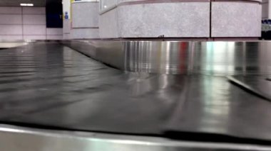 Havaalanında boş bavul kemerini taşımanın düşük açılı görüntüsü, genel halk gürültüsü.