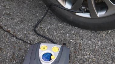 Elektrikli lastik enflasyonu araba elektrik sistemine bağlı. Yol kenarında araba lastiği pompalanıyor..