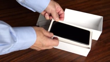 Yeni cep telefonlarını açan, kutudakileri çıkaran ve masaya koyan adamların ellerini kapat..