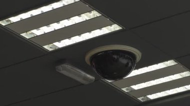 Tavana sabitlenmiş siyah cam güvenlik kamerası baloncukları üzerinde hareket eden insanların yansımaları..