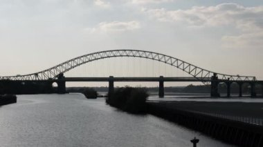 Akşamleyin İngiltere 'nin kuzeybatısında Widnes ve Runcorn arasında Silver Jubilee Köprüsü' nün arkasındaki demiryolu köprüsüne giren kısa tren..