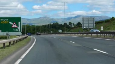 Galler 'in karlı dağ manzarasında A55 otoyolunda araba ön cam manzarası.