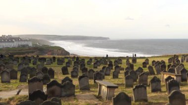 Akşamları deniz kenarındaki tepedeki Whitby mezarlığı. Akşamları deniz kenarındaki tepedeki Whitby mezarlığı. Uzak insanlar manzaranın tadını çıkarıyor.