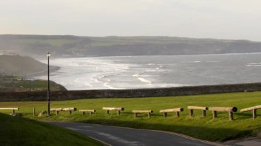 Kuzey Yorkshire kasabasının yüksek açılı manzarası Whitby limanı, plajı yıkayan beyaz dalgalar..