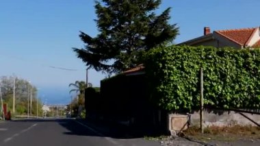 Zafferana Etnea köyündeki Viale de Gasperi caddesinden aşağıya, İyon deniz manzaralı, el kamerasıyla deniz kenarına doğru ilerliyoruz..