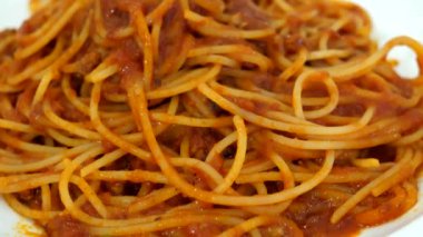 Kafe masasında beyaz tabakta soslu Sicilya spagettisi..