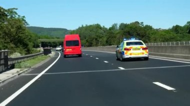 A55 HIGHway, WALES, UNITED KINGDOM - CIRCA HAZİRAN 2021: Galler otobanındaki trafiğin ön görüntüsü, A525 Rhyl yolu ile kavşağa doğru hızla ilerleyen acil durum ışıkları olan polis arabası.