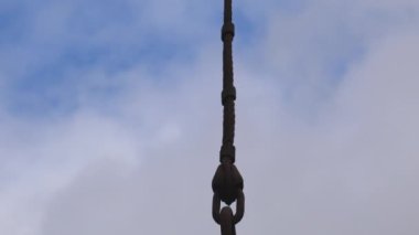  Bulutlu gökyüzüne karşı büyük paslı kaldırma kancasının aşağı eğimli görüntüsü.