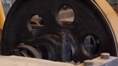 Eski karanlık bir fabrikanın içindeki eski su motorlu makinelerin bir parçası olarak dönen büyük düz kemerli makarayı kapat..