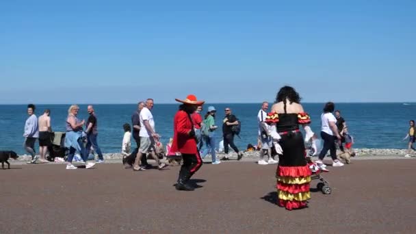 Llandudno Walles イギリス Circa 2021年6月 メキシコの伝統的な服を着たストリートエンターテイナーカップルが有名なウェールズの海辺の観光リゾートでビーチで踊っている 人々が見ている — ストック動画