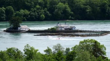 Kanocu adam, küçük adanın akıntılarında, Menai Boğazı 'nın ortasındaki iki evle ya da Anglesey adası ile Galler anakarası Menai nehri arasında antrenman yapıyor..