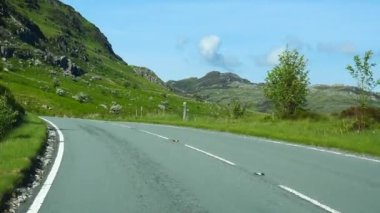 Kuzey Galler, Snowdonia Dağları 'nın güzel manzarasında güneşli bir günde A4086 kırsal yolunda araba manzarası..