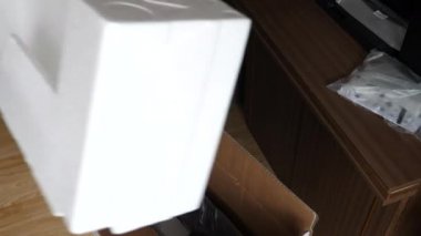 Yeni 4K akıllı televizyon seti açan adam; karton kutu aksesuar, televizyon standı parçaları ve polistiren yastıklardan çekiyor. Eski televizyonu kaldırmaya çalışıyor ama güvenli olmadığını fark ediyor..