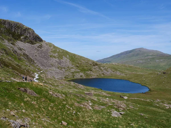 Snowdonia Ulusal Parkı 'ndaki Llyn Teyrn Gölü' nün kıyısındaki Snowdon Dağı 'ndan Kuzey Galler' e doğru yürüyen madenciler..