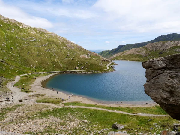 Glaslyn Gölü kıyısında Snowdonia Dağı 'nın eteklerinde dinlenen yürüyüşçüler İngiltere' nin Galler Ulusal Parkı 'nda.