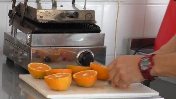 Kock eller barman skär apelsiner för juice — Stockvideo