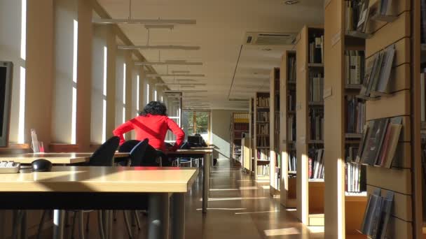 Mujer rizada caminando en la biblioteca — Vídeos de Stock