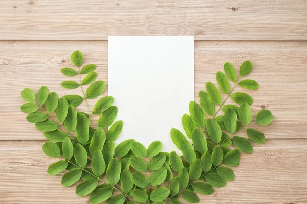 Border or banner of Green leaves on the wooden background and paper for notes. Top view. plant and leaf. organic temlate with space for text. watercolor paper. Ecology, nature