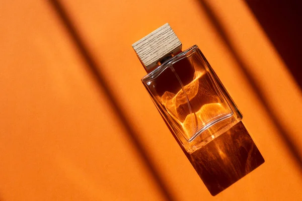 Frasco transparente de perfume sobre fondo naranja —  Fotos de Stock