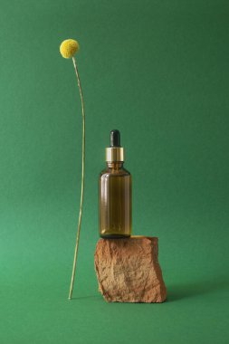 Metalik kapaklı ve kurutulmuş sarı çiçekli kehribar damlası şişesi..