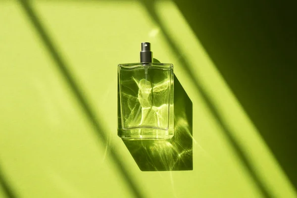 Transparente Flasche Parfüm mit Spray auf gelb-grünem Hintergrund — Stockfoto