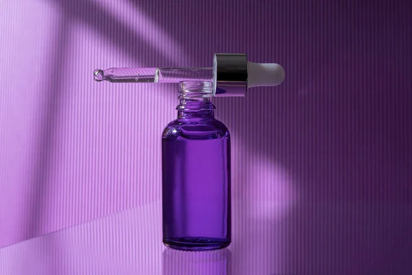 Bouteille compte-gouttes ouverte en verre violet avec sérum et pipette. — Photo