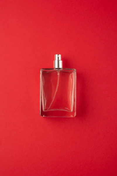 Transparent bottle of perfume with spray on red surface. — Stock Photo, Image