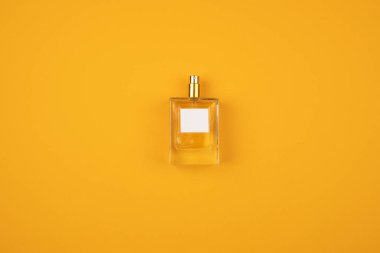 Turuncu yüzeyine sprey sıkılmış saydam bir parfüm şişesi..