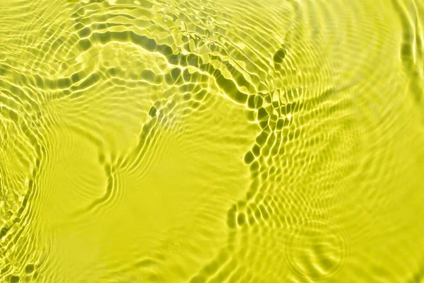El agua se derrama sobre un fondo amarillo verde claro. Hermosas explosiones y resplandor. —  Fotos de Stock