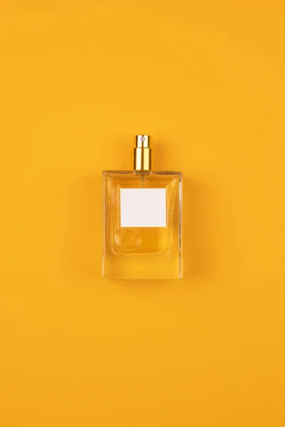Átlátszó parfümös üveg narancsszínű felületre szórva. — Stock Fotó
