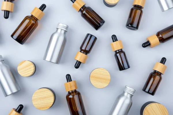 Botellas cuentagotas de vidrio ámbar de diferentes tamaños con tapa de bambú y botellas metálicas. —  Fotos de Stock