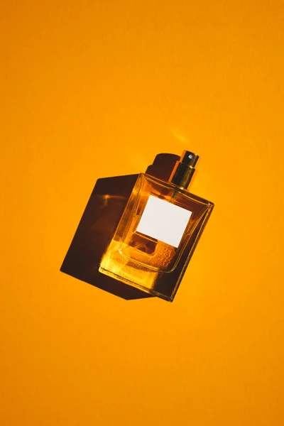 Przezroczysta butelka perfum z aerozolem na pomarańczowej powierzchni. Przezroczyste szkło bez pokrywy. — Zdjęcie stockowe
