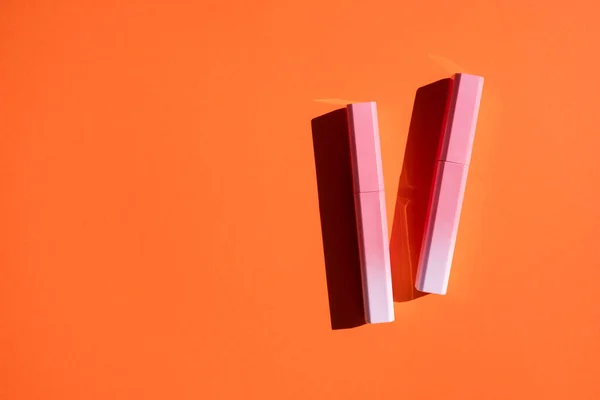 Brilho labial em caso de gradiente rosa a branco sobre fundo laranja. — Fotografia de Stock