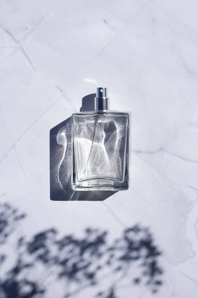 Прозрачная бутылка духов с брызгами на поверхности белого мрамора. — стоковое фото