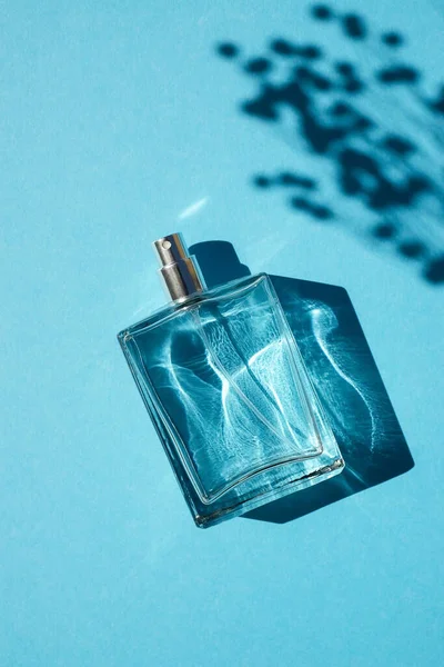 Transparente Flasche Parfüm auf blauem Hintergrund. Duftpräsentation mit Tageslicht — Stockfoto